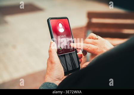 Avertissement d'appel d'arnaque sur l'écran du smartphone refusé par la femme mature. Concept d'appel suspect. Banque D'Images
