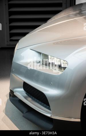 Gros plan d'un phare avant d'hypercar Bugatti Chiron et d'une carrosserie argentée exposés lors d'un salon automobile Banque D'Images