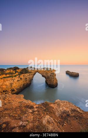 Une photographie sereine de coucher de soleil longue exposition capturée à Praia de Albandeira en Algarve, Portugal. La scène présente une roche calcaire unique et élégante Banque D'Images