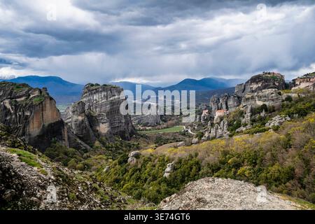 Vue panoramique sur les formations rocheuses et les monastères des Météores depuis le point de vue principal en Grèce sous les nuages de tempête dramatiques. Puits de pluie visibles et atmos Banque D'Images