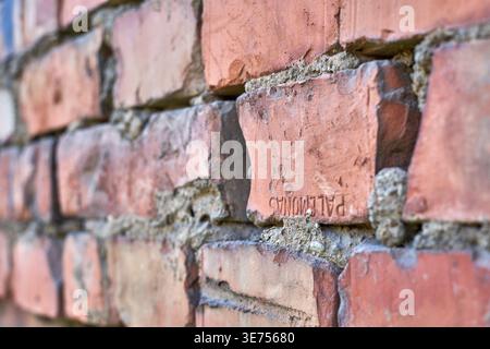 Photographie en gros plan d'un mur de briques vieilli montrant des briques d'argile rouges et oranges patinées avec des joints de mortier rugueux. Une brique proéminente dans le Banque D'Images