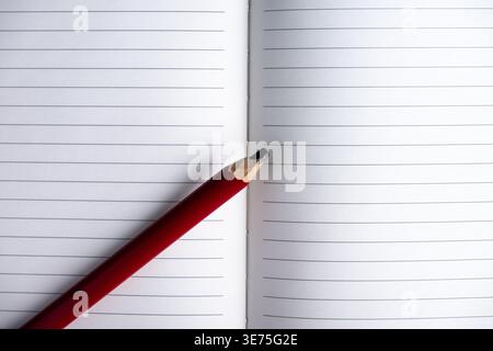 Cahier ligné ouvert avec crayon sur fond blanc. Composition vue de dessus avec espace de copie, idéal pour l'écriture, la planification, la journalisation et la productivité co Banque D'Images