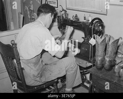 Image historique d'un cordonnier réparant des bottes de cow-boy à l'aide d'une machine à coudre à l'intérieur d'un magasin de bottes à Alpine, Texas, mai 1939. Photographie de Russell Lee. Banque D'Images
