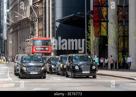 Les taxis noirs emblématiques de Londres attendent aux feux de circulation dans le centre de Londres, Royaume-Uni Banque D'Images