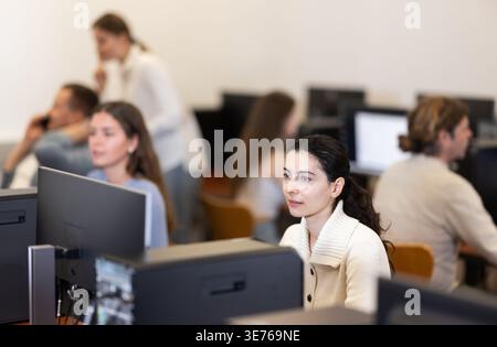 L'étudiante des cours d'informatique regarde l'écran de moniteur, les types sur le clavier et fait le travail Banque D'Images