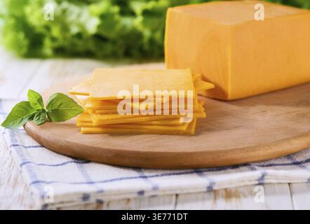 Cheddar au fromage naturel tranché sur une table en bois blanc, mise au point sélective Banque D'Images