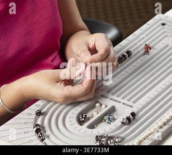 Close up d'enfiler des perles sur le fil de collier de perles bracelet ou artistique Banque D'Images