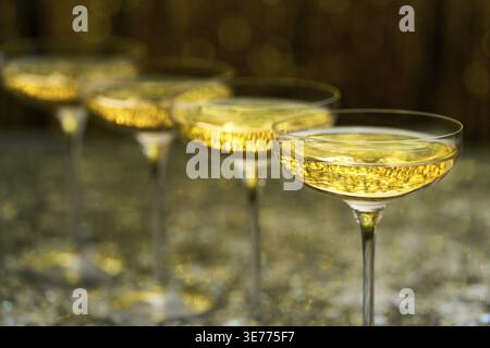Verres de champagne pétillant sur un fond élégant doré, mise au point sélective. Rangée de verres à champagne remplis. Beaucoup de verres remplis de champagne Banque D'Images