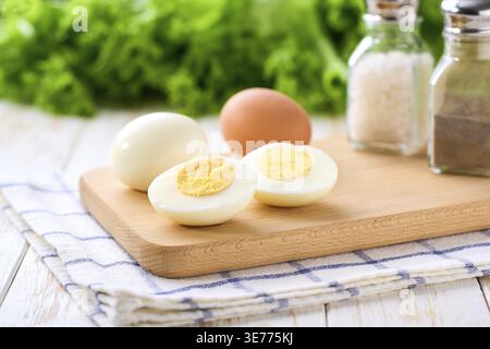 Oeufs durs pelés et coupés en deux avec du sel et du poivre sur une table blanche, mise au point sélective Banque D'Images