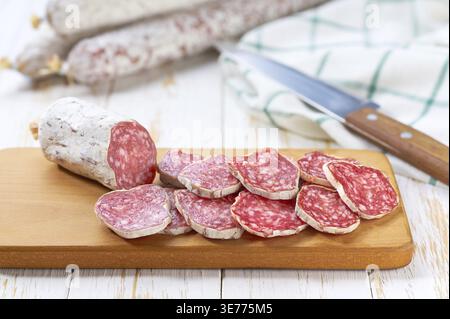 Tranches de délicieux fuet de saucisse espagnole sur une table en bois blanc, mise au point sélective Banque D'Images