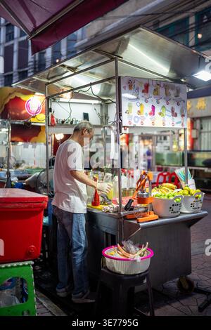 Vendeur fabriquant et vendant des jus de fruits fraîchement pressés, des smoothies et des boissons aux fruits au marché de rue local. Banque D'Images