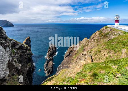 Vue panoramique du phare de Cabo Ortegal en Galice. La tour blanche avec une bande rouge surplombe des falaises abruptes et les empilements de roches de Aguillóns, où th Banque D'Images