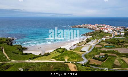 Superbe vue aérienne de Caión, Espagne. Cette photo capture la plage de sable blanc, les vagues de l'Atlantique, le village de pêcheurs sur la péninsule, et le Gree luxuriant Banque D'Images