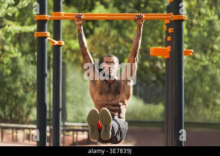 Homme afro-américain faisant l-sit sur des barres horizontales Banque D'Images
