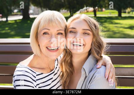 Fille heureuse avec mère âgée assise dans le parc Banque D'Images