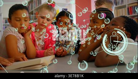 Rassemblement du groupe d'enfants et de l'animateur penché sur la table basse de la bibliothèque, avec une superposition de livre ouvert Banque D'Images