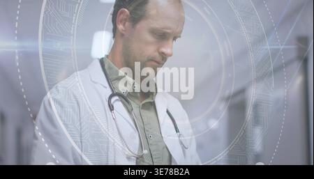 Médecin debout en blouse blanche examinant la superposition AR circulaire dans le couloir clinique, stéthoscope Banque D'Images