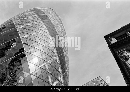 Le Gherkin Building, City of London, UK, regardant vers le haut, avec les bâtiments adjacents, en monochrome Banque D'Images