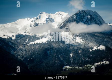 Vue sur les majestueuses montagnes enneigées perce le ciel, leurs sommets voilés de nuages éthérés, comme vu du train, train de Lucerne à Interlaken Banque D'Images