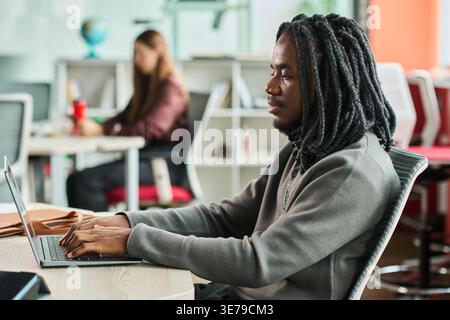 Homme noir travaillant sur ordinateur portable dans le bureau moderne pour une utilisation professionnelle Banque D'Images