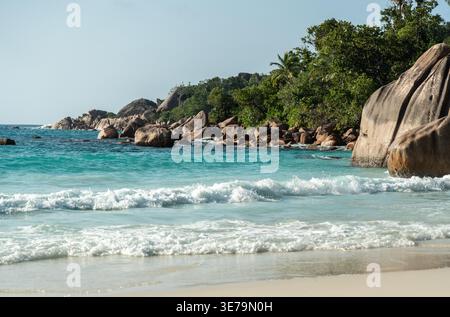Plage tropicale des Seychelles avec mer turquoise, rochers de granit, végétation luxuriante de palmiers, et vagues claires parfaites pour des vacances exotiques, nature backgr Banque D'Images