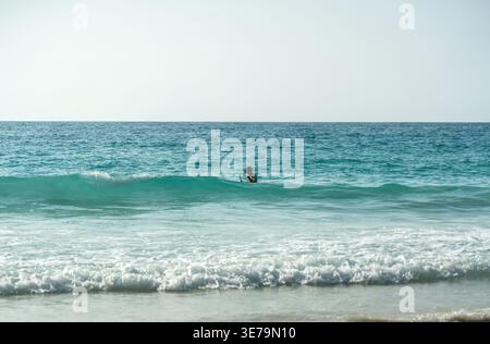 Nageur tropical faisant de la plongée en apnée seul dans un océan turquoise clair près des vagues calmes de la plage sous le soleil sur une côte sereine des Seychelles Banque D'Images