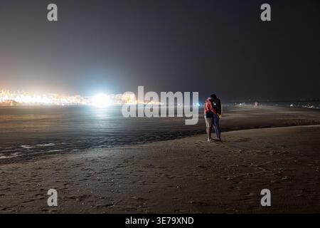 Un jeune couple partage une étreinte intime sur la plage de Matalascañas, Almonte, Huelva, Espagne, sous le ciel nocturne lors d'une chaude soirée d'été. Banque D'Images