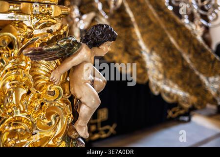 Gros plan d'un ange sculpté sur le paso mystère Exaltación pendant la semaine Sainte à Séville. La verrière élaborée du palio est légèrement floue dans le backgroun Banque D'Images