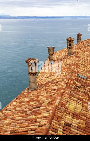 Toit en terre cuite avec cheminées surplombant la mer Adriatique dans le nord de l'Italie. Vue panoramique sur la côte. Banque D'Images