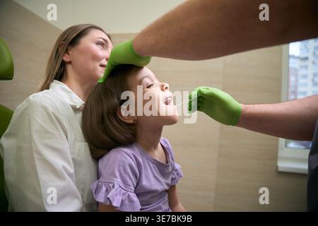 Femme adulte et homme examinant la fille en salle médicale Banque D'Images