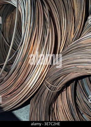 Une photo détaillée de plusieurs grandes bobines de fil d'acier industriel épais et légèrement rouillé ou de barres d'armature liées ensemble, créant un motif circulaire répétitif Banque D'Images