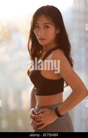 Femme chinoise dans le soutien-gorge de sport debout avec les mains sur la taille à l'intérieur Banque D'Images