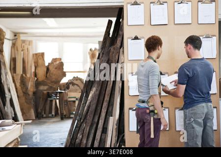 La femme et l'homme de l'équipe de travailleurs d'usine contrôle de stock du projet dans une usine à bois. Banque D'Images