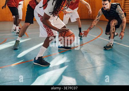 Homme du moyen-Orient avec des dreadlocks jouant au basket-ball avec des coéquipiers sur le terrain Banque D'Images