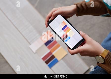 Mains de concepteur féminin mixte-race prenant en photo la palette de couleurs tout en se tenant debout dans le bureau Banque D'Images