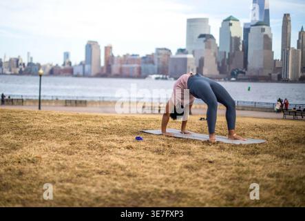 Femme afro-américaine faisant la pose de yoga de maison de roue dans le parc Banque D'Images