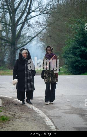 Femme noire et femme âgée caucasienne portant des vêtements chauds parlant tout en marchant ensemble sur la route pendant l'hiver Banque D'Images