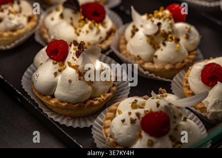 Gros plan d'un dessert meringue garni de fraises fraîches, de groseilles rouges et de myrtilles. Pâtisserie sucrée sur l'affichage avec muffins en arrière-plan, concept de Banque D'Images