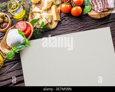 Assortiment de nourriture méditerranéenne sur une table en bois rustique. Le papier blanc au centre fournit un espace de copie pour les recettes, les menus ou les concepts alimentaires. Banque D'Images