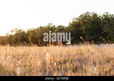 Femme afro-latina en vêtements actifs courant le long de la route au coucher du soleil Banque D'Images