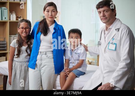 Mère de race mixte visitant le médecin avec son fils et sa fille pour le bilan annuel en clinique Banque D'Images
