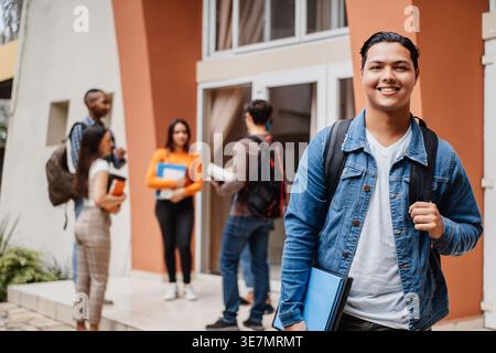 Étudiant hispanique avec sac à dos debout près de camarades de classe sur le campus Banque D'Images