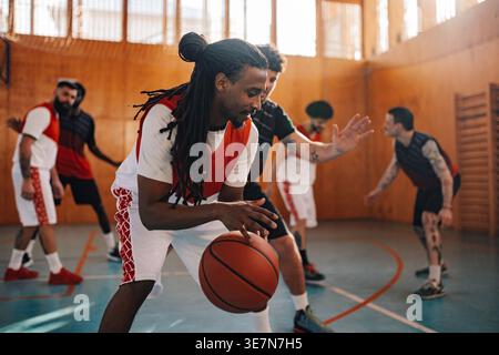 Homme du moyen-Orient jouant au basket-ball avec ses coéquipiers pendant la séance d'entraînement sur un court intérieur Banque D'Images