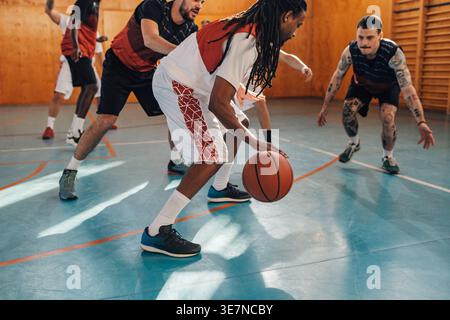 Homme du moyen-Orient jouant au basket-ball avec ses coéquipiers pendant la séance d'entraînement sur un court intérieur Banque D'Images
