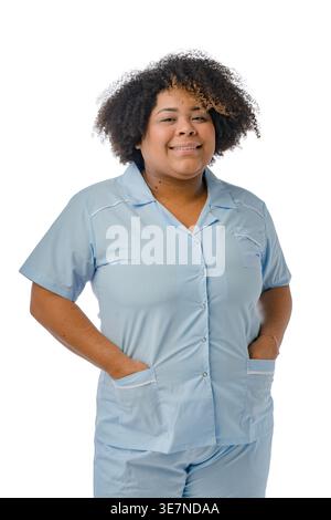 Femme hispanique de grande taille avec afro bouclé portant un uniforme bleu debout avec les mains dans les poches sur fond blanc dans le studio Banque D'Images