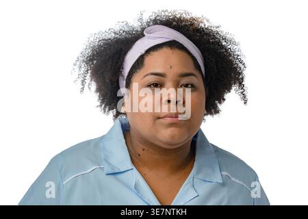 Femme hispanique de grande taille avec afro bouclé portant un uniforme bleu et un bandeau debout sur fond blanc en studio Banque D'Images