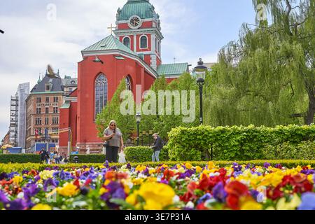 Une scène vibrante de printemps mettant en vedette Sankt Jacobs kyrka (église Saint-Jacques), une église historique rouge frappante avec un dôme en cuivre vert et une tour d'horloge Banque D'Images