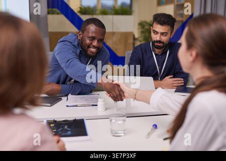 Groupe diversifié de médecins ayant rencontré des mains serrant dans la salle de conseil Banque D'Images