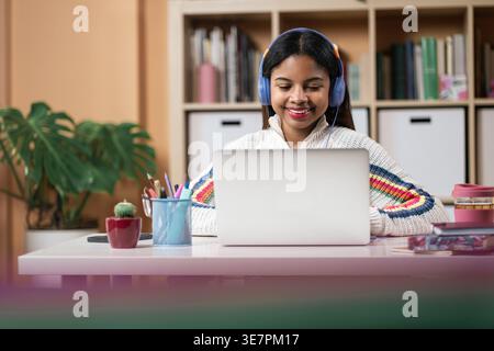 Étudiante afro-américaine souriante utilisant un ordinateur portable assistant à des cours en ligne à la maison Banque D'Images