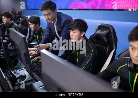 Homme chinois sérieux entraînant des joueurs masculins jouant à l'esport sur ordinateur dans l'arène Banque D'Images
